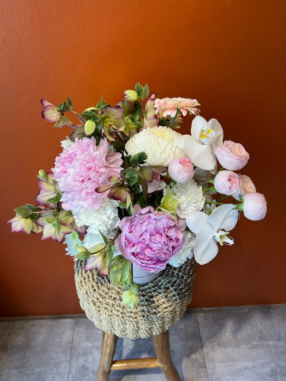 Lush pastel peony arrangement in a rattan basket — ceremony piece