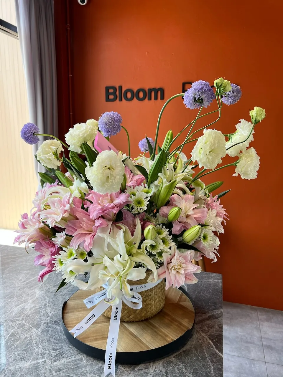 Compact pastel arrangement with purple allium, pink lilies and chrysanthemums