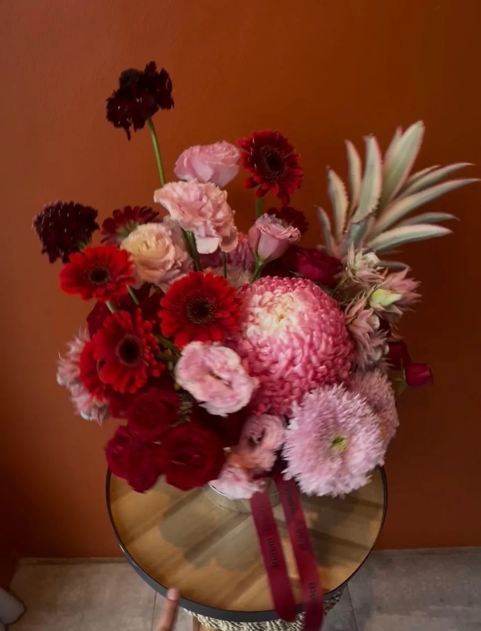 Dramatic red and pink arrangement with scabiosa, gerbera and pineapple foliage
