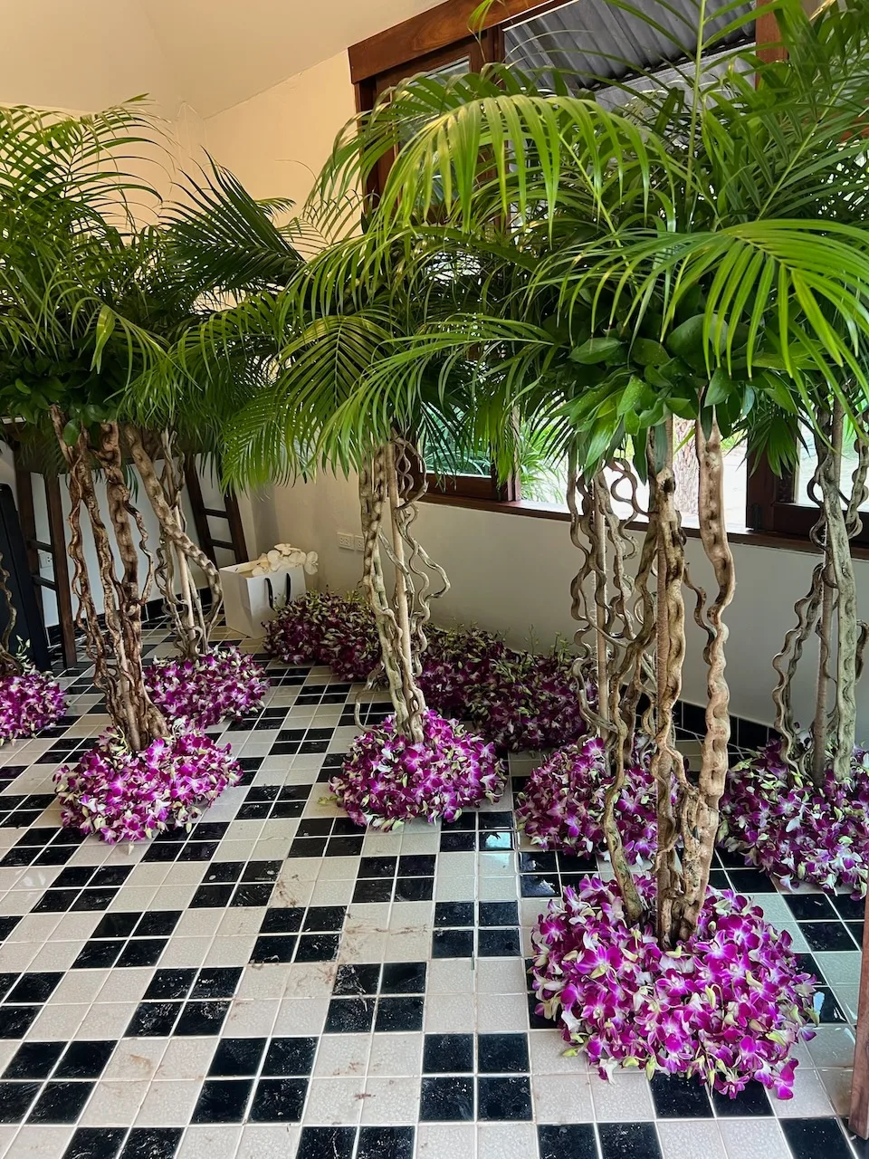 Event installation with palm trees wrapped in purple orchid clusters by Bloom Room Studio, Koh Samui