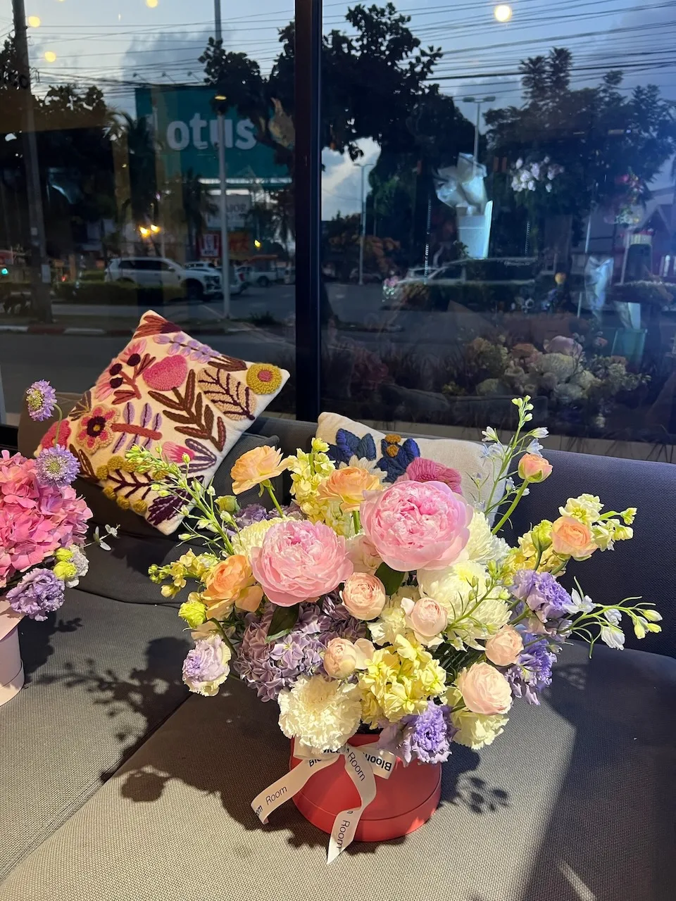 Pink peony, ranunculus and snapdragon flowerbox in shop window at dusk
