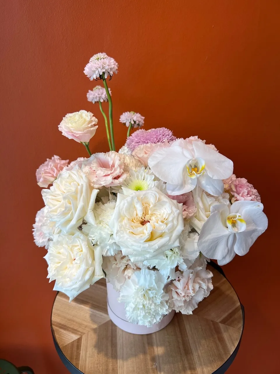 Lush hat box arrangement with cream garden roses, white orchids, pink carnations and lisianthus