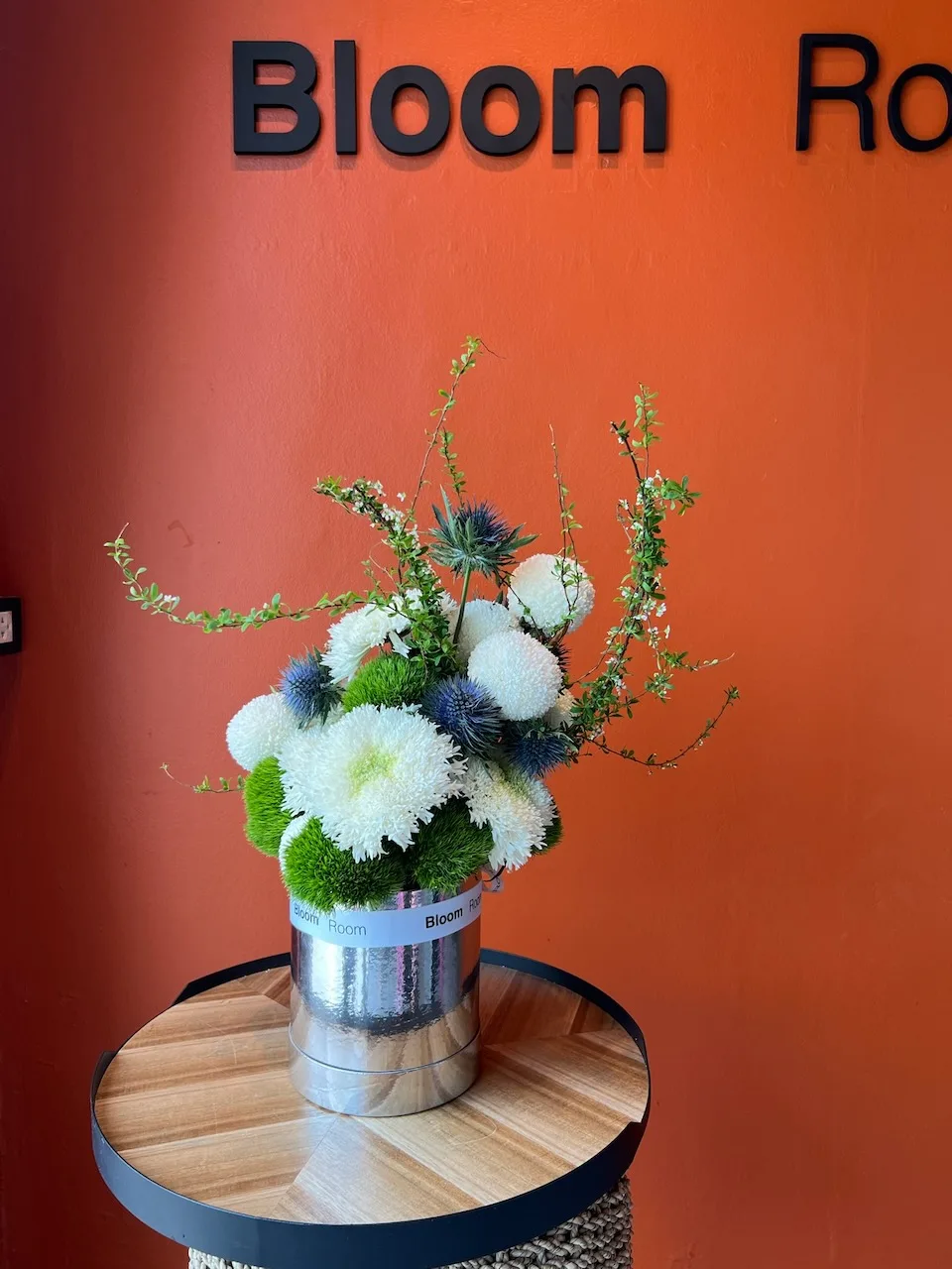 Silver Bloom Room box with white chrysanthemums, blue thistle and green accents on a side table