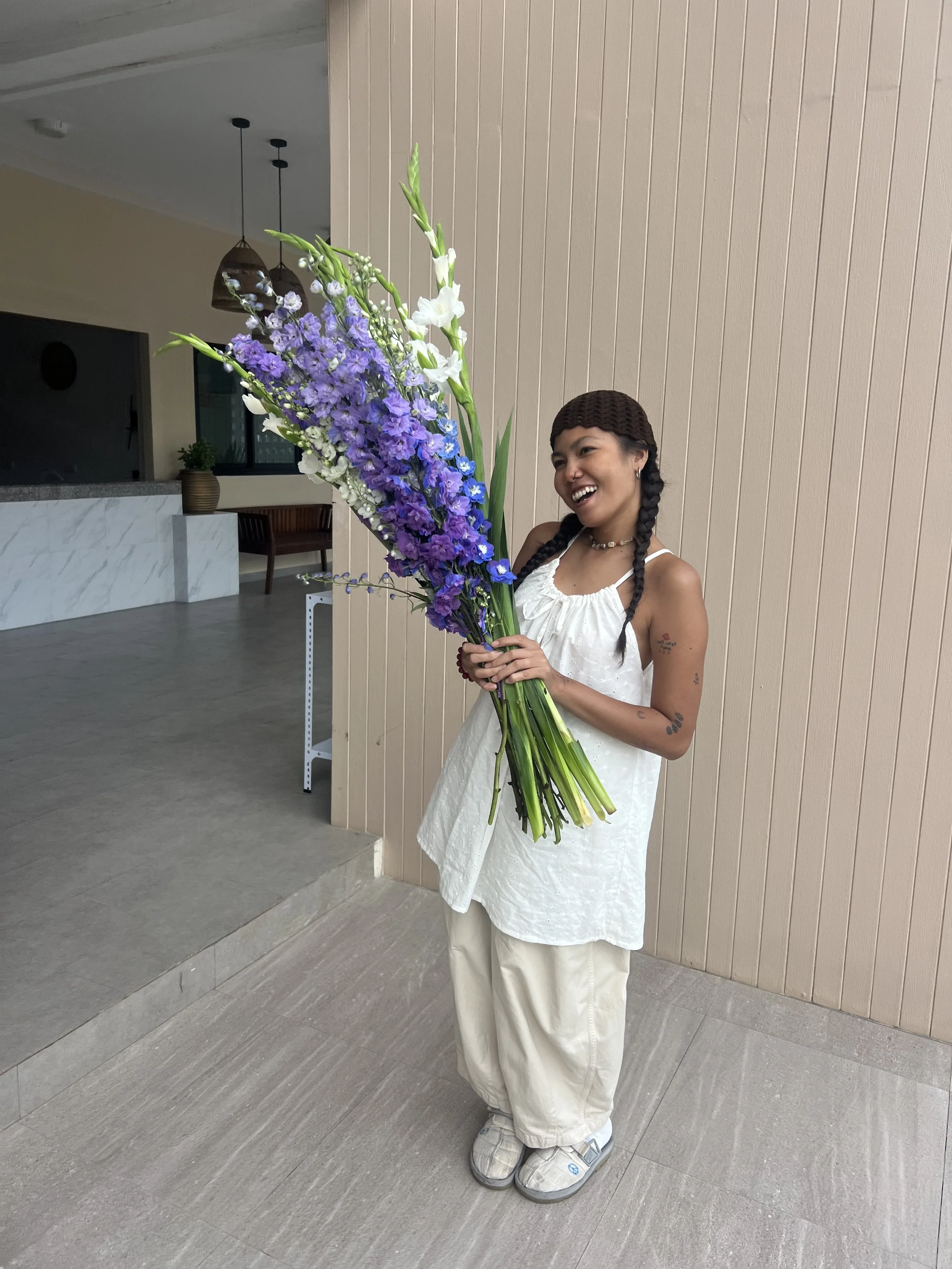 Woman holding a bouquet of purple delphinium at Bloom Room Studio, Koh Samui